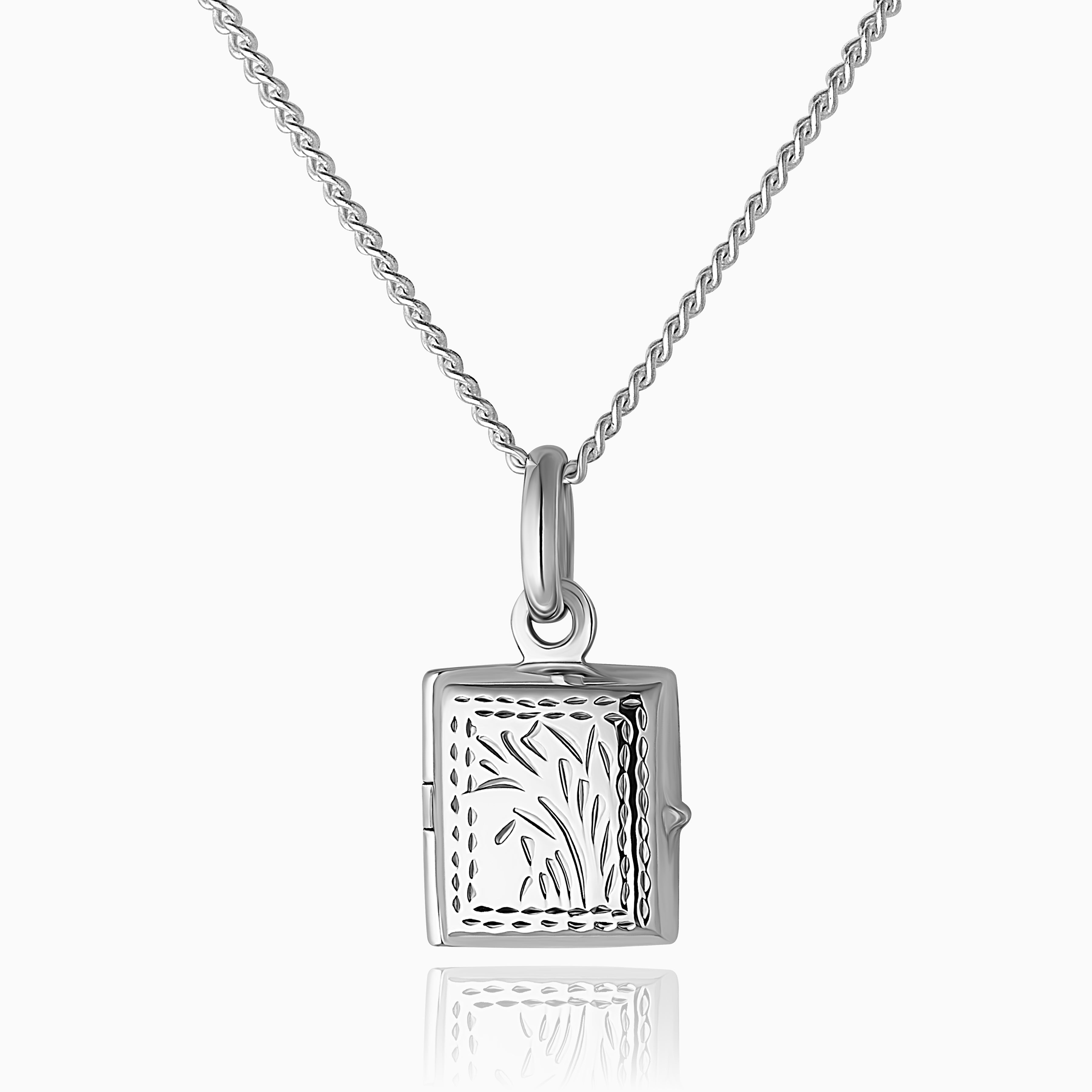 Photo of a 925 sterling silver book locket for children with a traditional foliate design on the front of the locket placed on a curb chain
