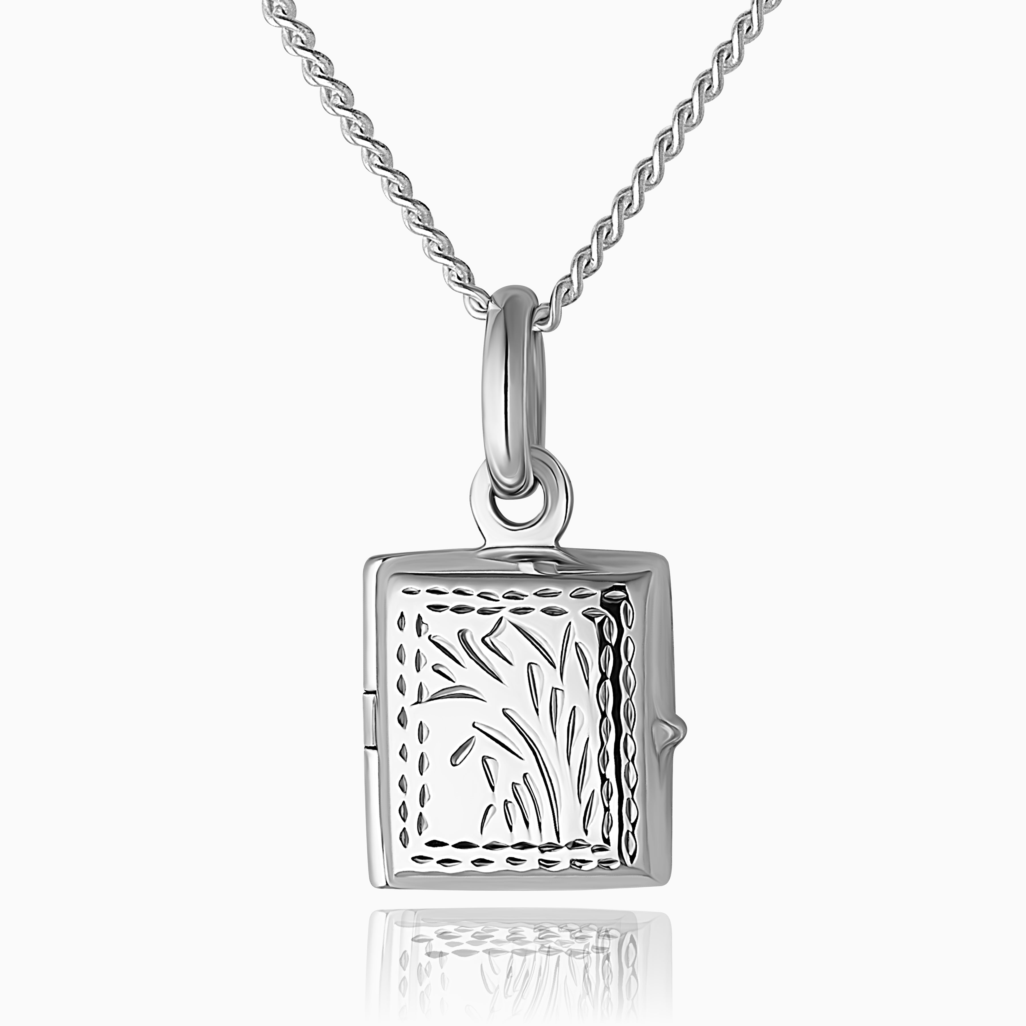 a close up photo of a 925 sterling silver book locket for children with a traditional foliate design on the front of the locket placed on a curb chain
