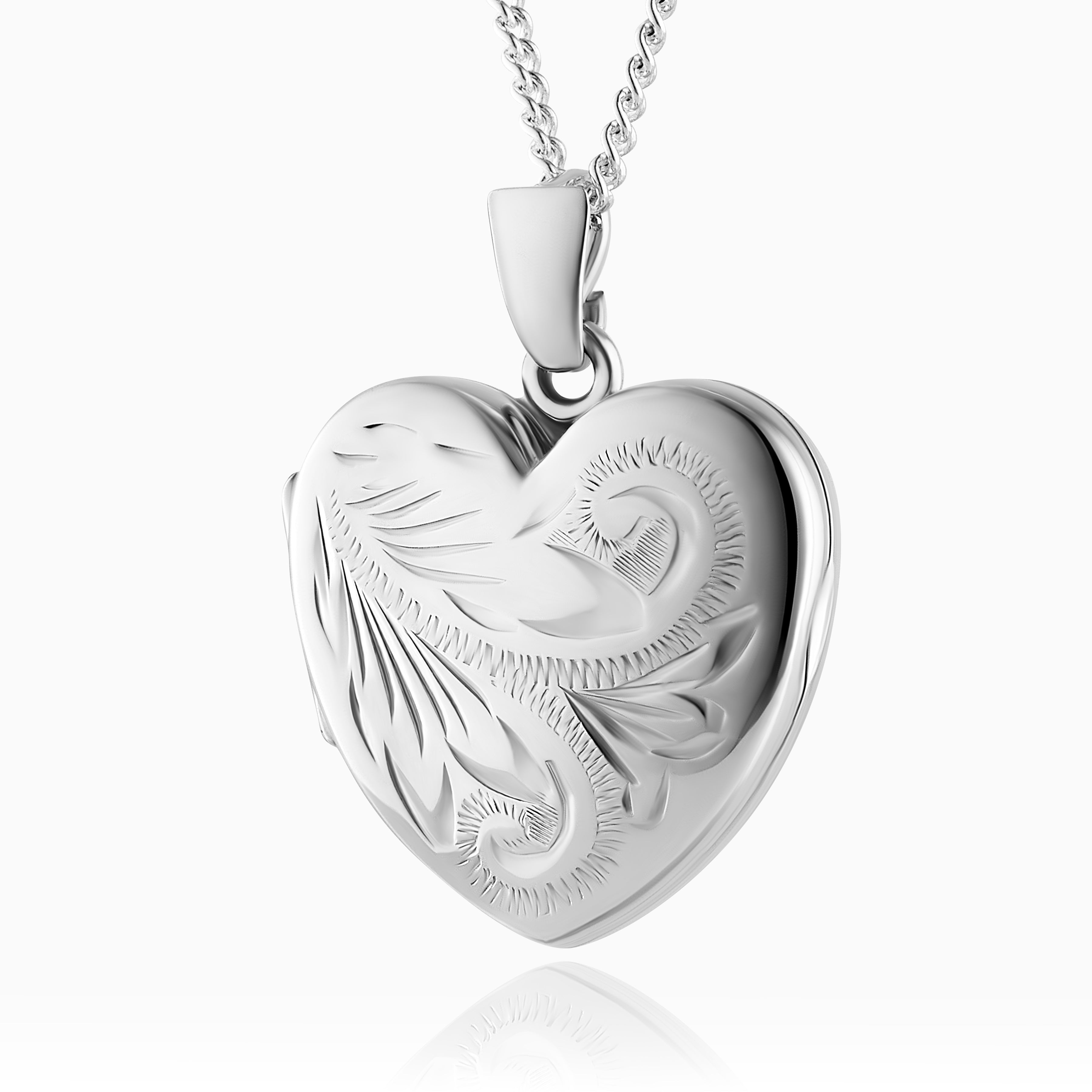 Silver heart-shaped locket with intricate designs on a white background