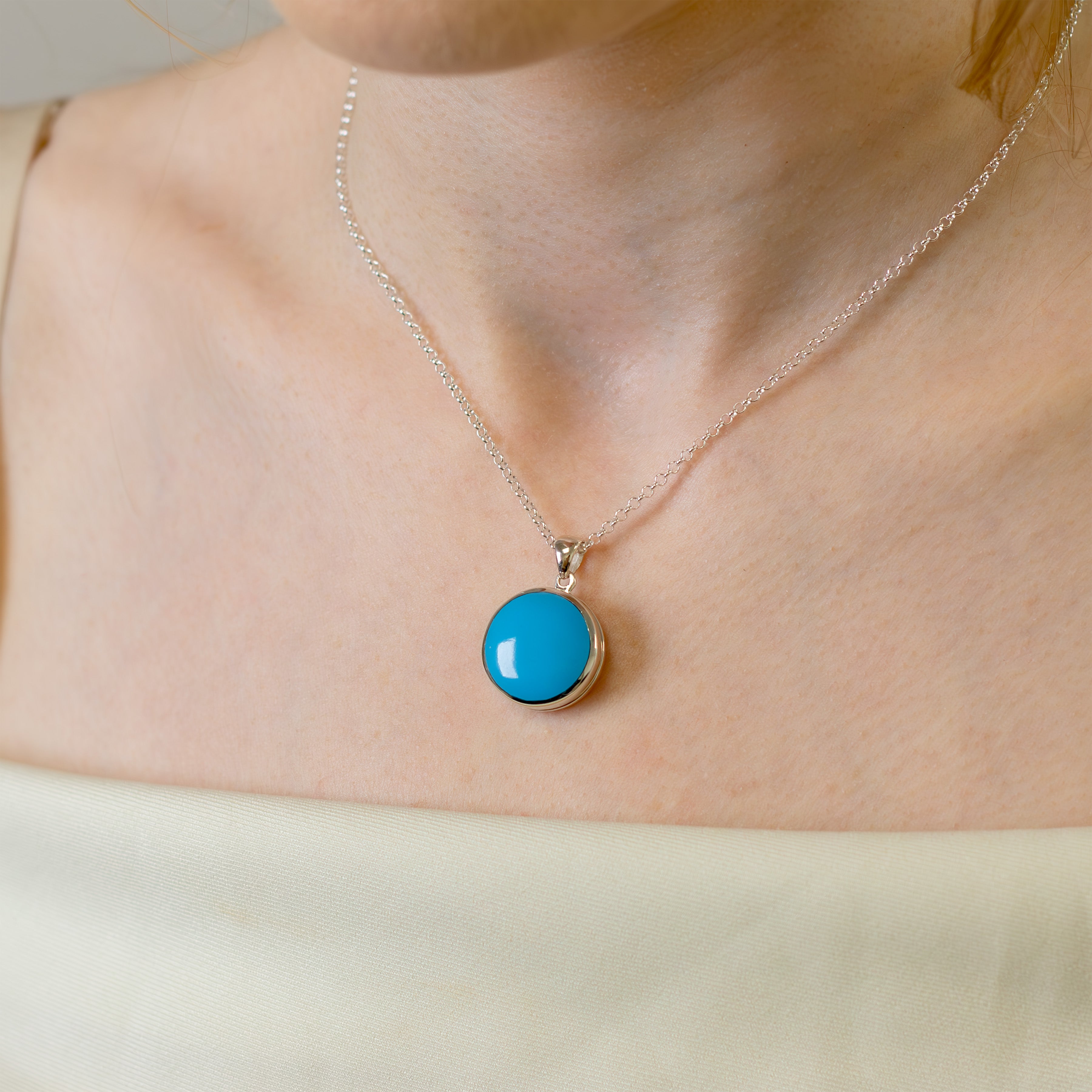 model wearing a sterlig silver round locket set with blue turquoise