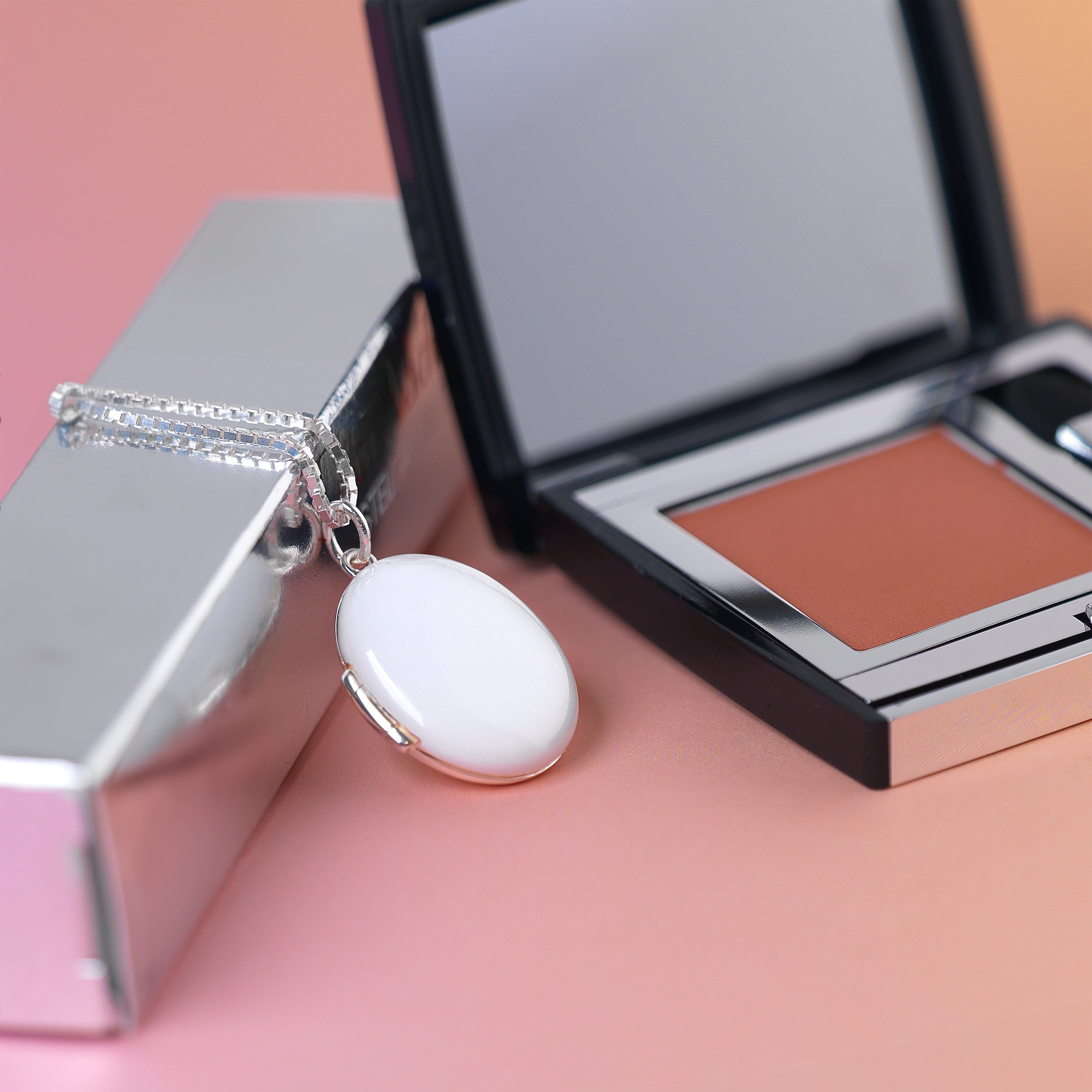 photo of a 925 sterling silver oval locket enamelled in a high gloss white and placed on a box chain.