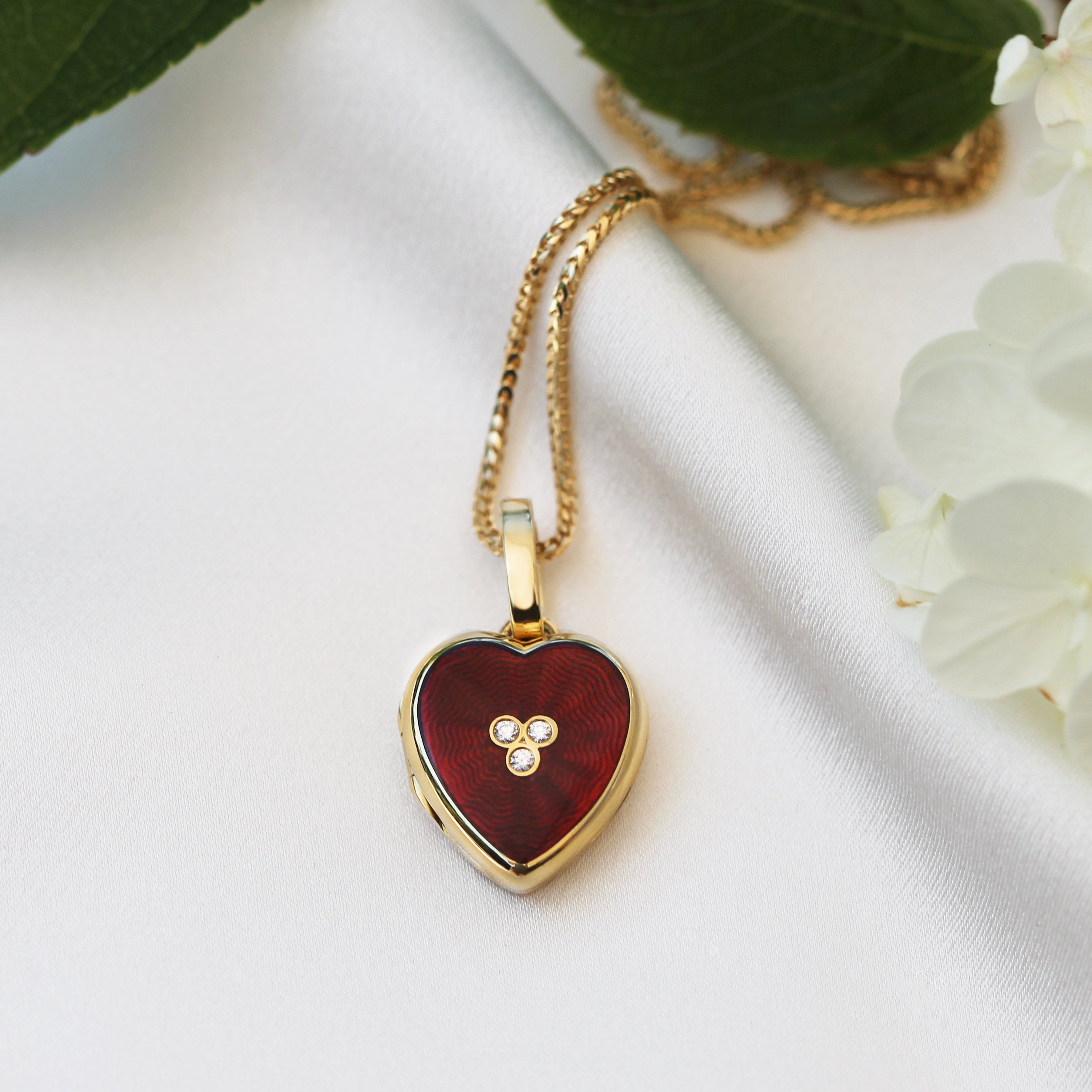 18 ct gold heart locket set with red guilloche enamel and 3 central diamonds on an 18 gold spiga chain
