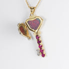 Open view of an 18 ct gold locket in the shape of a key set with diamonds and rubies, on an 18 ct gold trace chain