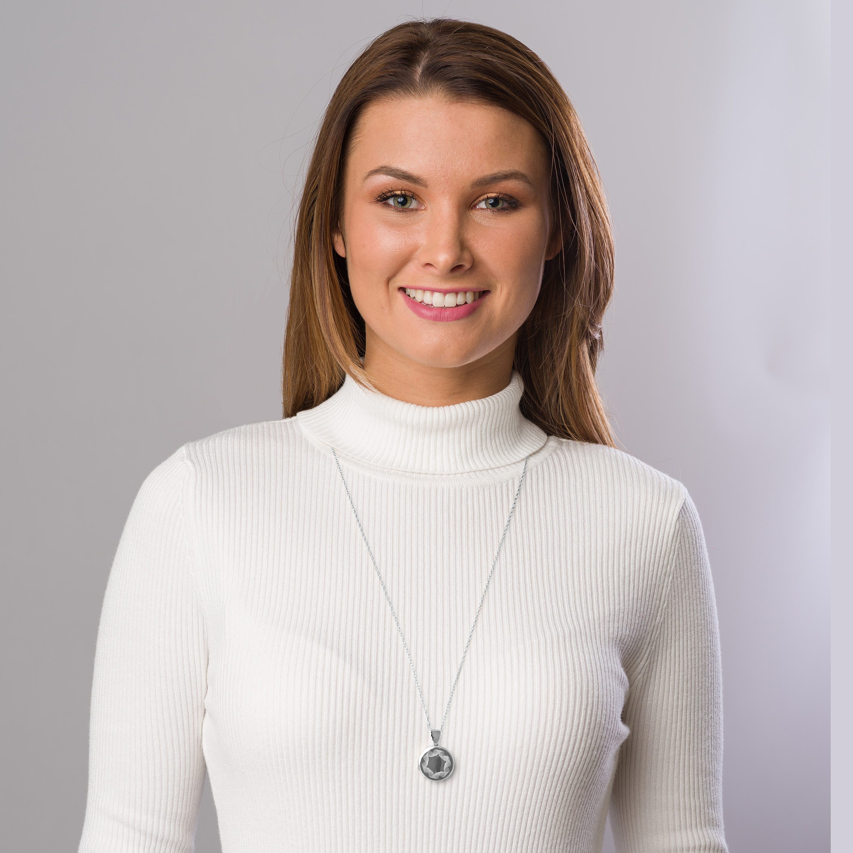 Model wearing a sterling silver round locket engraved with a ribbon design on a sterling silver chain