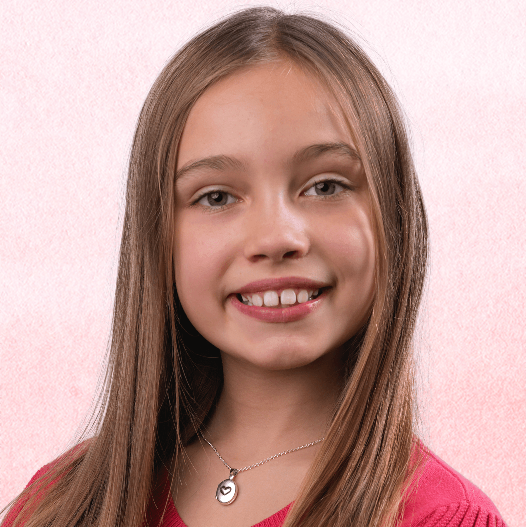 Child wearing a small oval sterling silver locket embossed with a heart on the front, on a sterling silver chain.