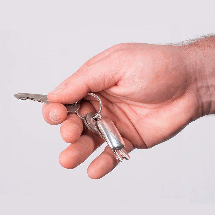 Model holding a sterling silver dog tag locket on a sterling silver dog tag keyring with keys