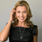 Model wearing a sterling silver book locket with a raised rose on the front, on a sterling silver curb chain