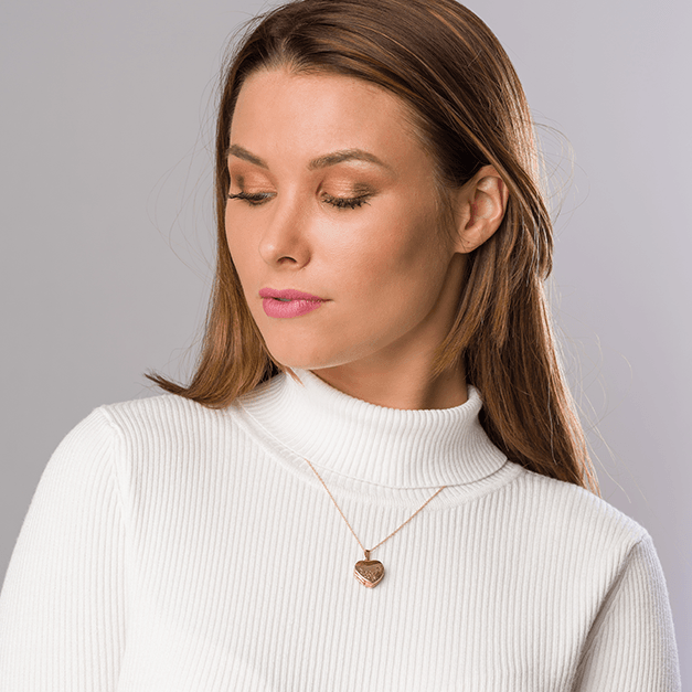 Model wearing a 9 ct gold 4-photo heart locket with a floral engraving on a 9 ct gold curb chain