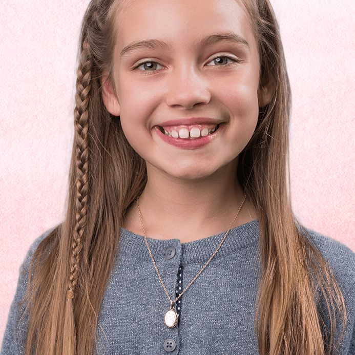 Model wearing a petite 9 ct gold child's oval locket engraved with a unicorn on a 9 ct gold rope chain