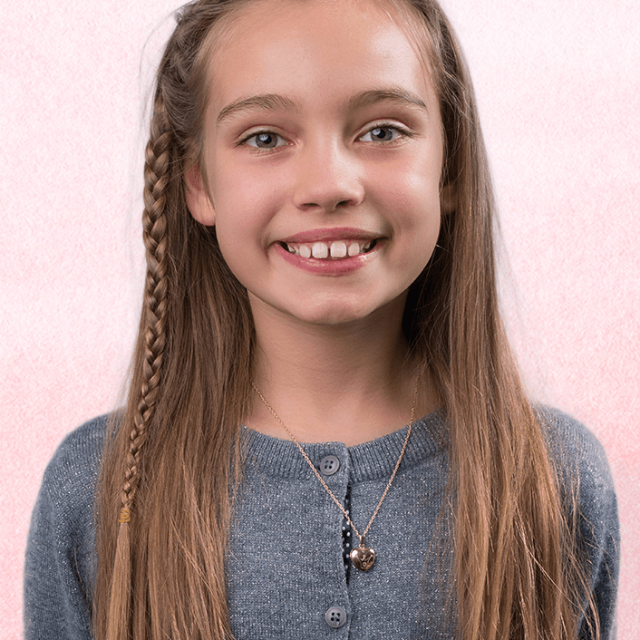 Model wearing a petite 9 ct gold heart locket engraved with a crown on a 9 ct gold rope chain.