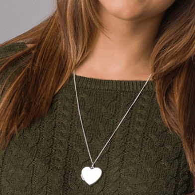 Model in green jumper wearing a sterling silver large heart shape locket.