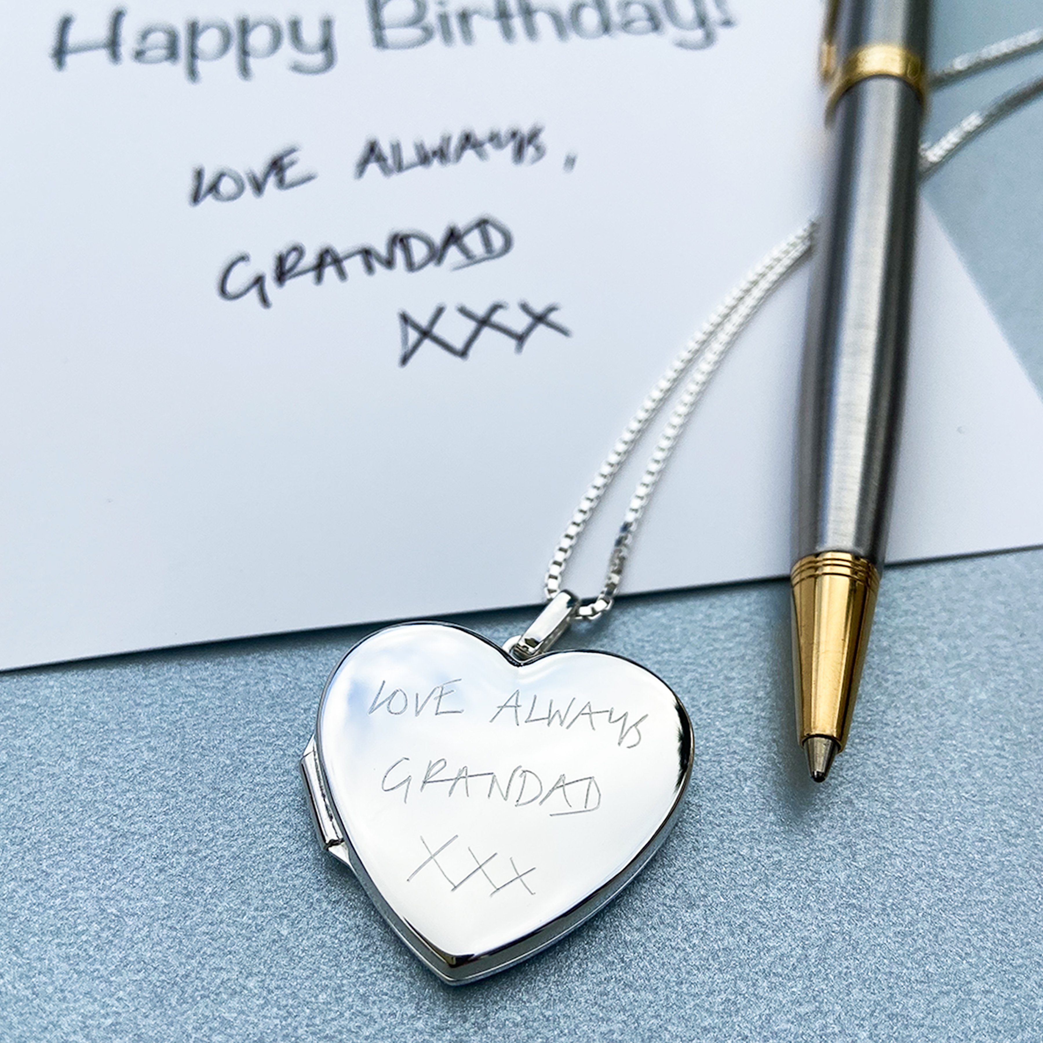 A copyhandwriting example on the front of the large polished sterling silver heart locket, set on a sterling silver box chain.