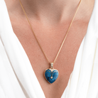 Model wearing an 18 ct gold heart locket set with blue guilloche enamel and diamonds on an 18 ct gold franco chain