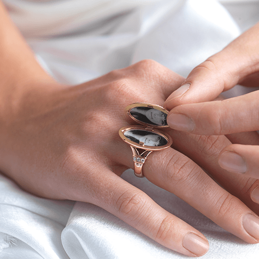 Model holding open an 18 ct rose gold oval locket ring.