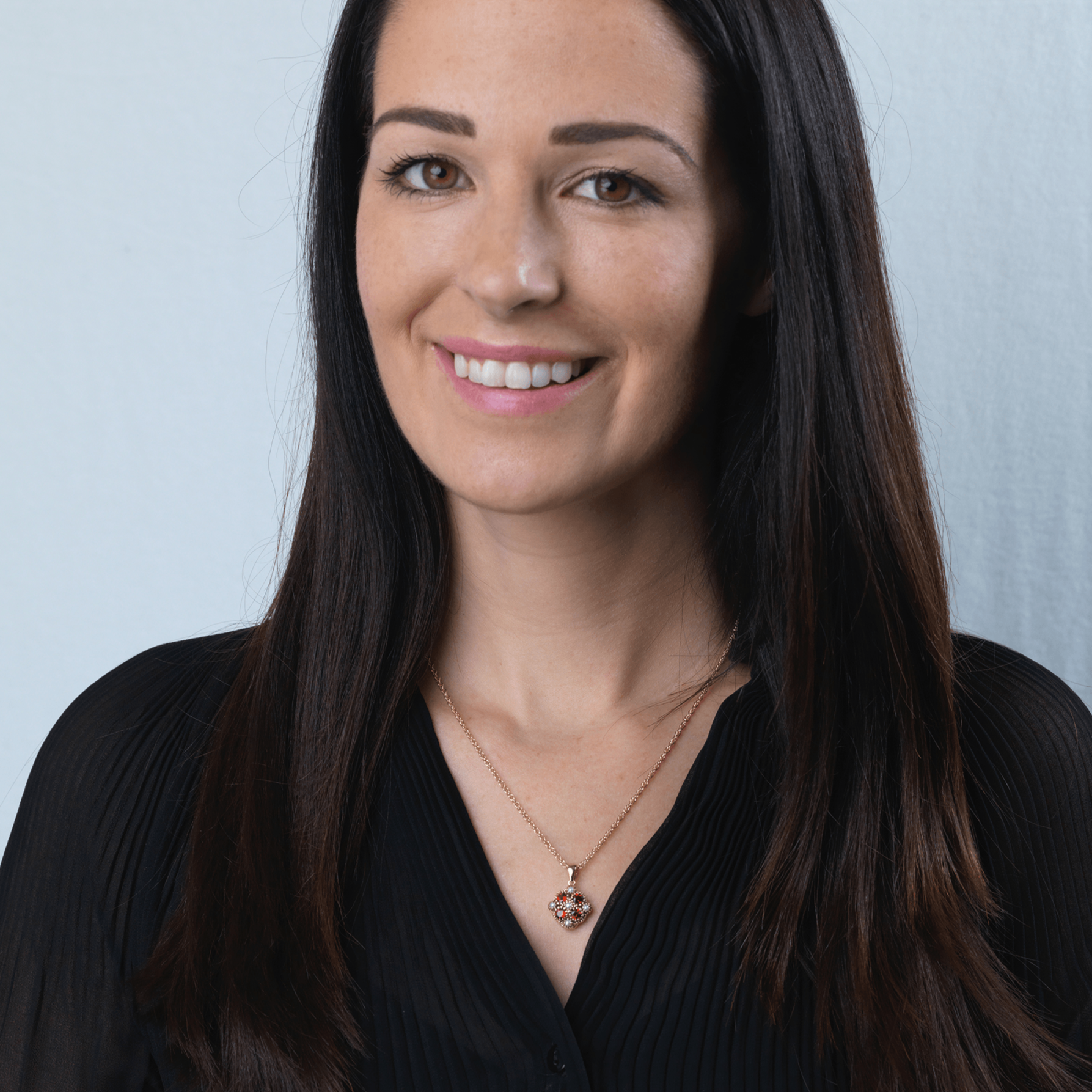 Model wearing a 9 ct gold tipped square locket set with garnets and seed pearls, on a 9 ct rope chain
