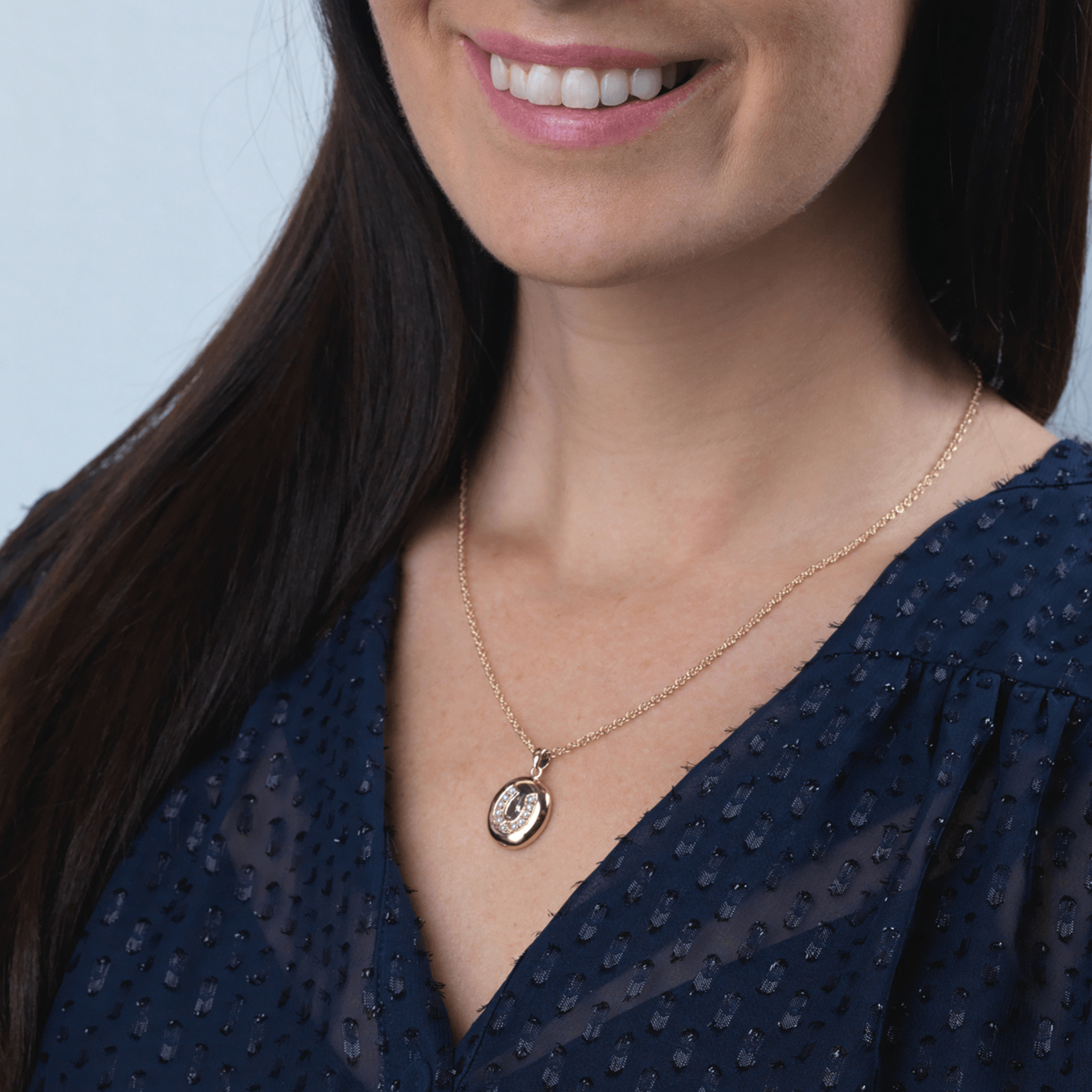 Model wearing a 9 ct gold oval locket set with seed pearls in a horseshoe design on a 9 ct gold rope chain