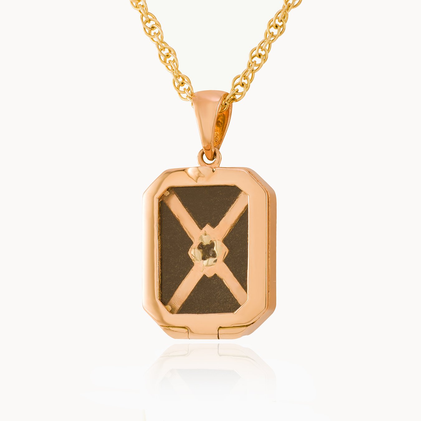 View of glass back of a 9 ct rose gold tabular locket on a 9 ct rose gold rope chain.