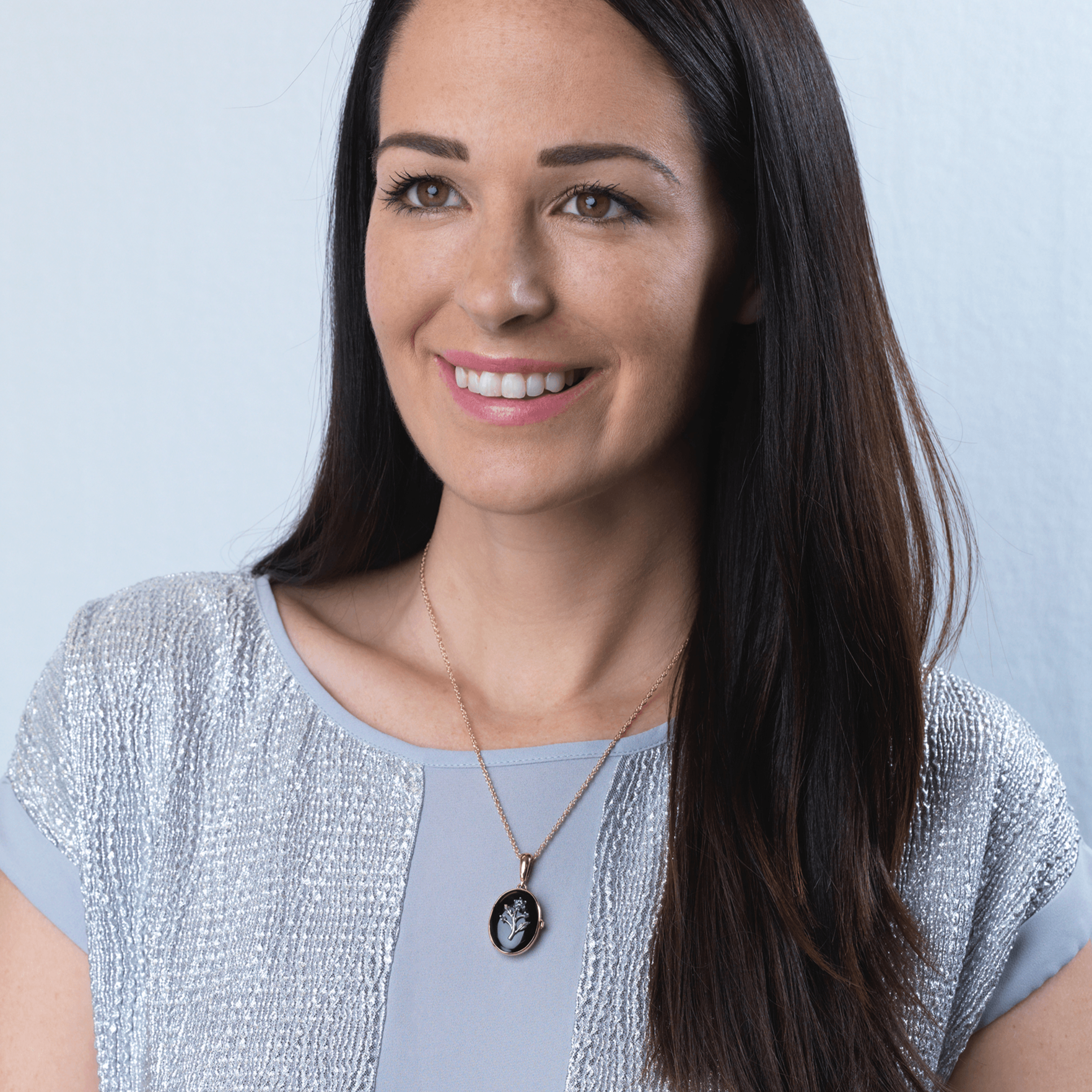 Model wearing a 9 ct gold oval locket set with diamonds and a white gold floral design on an onyx background, on a 9 ct gold rope chain