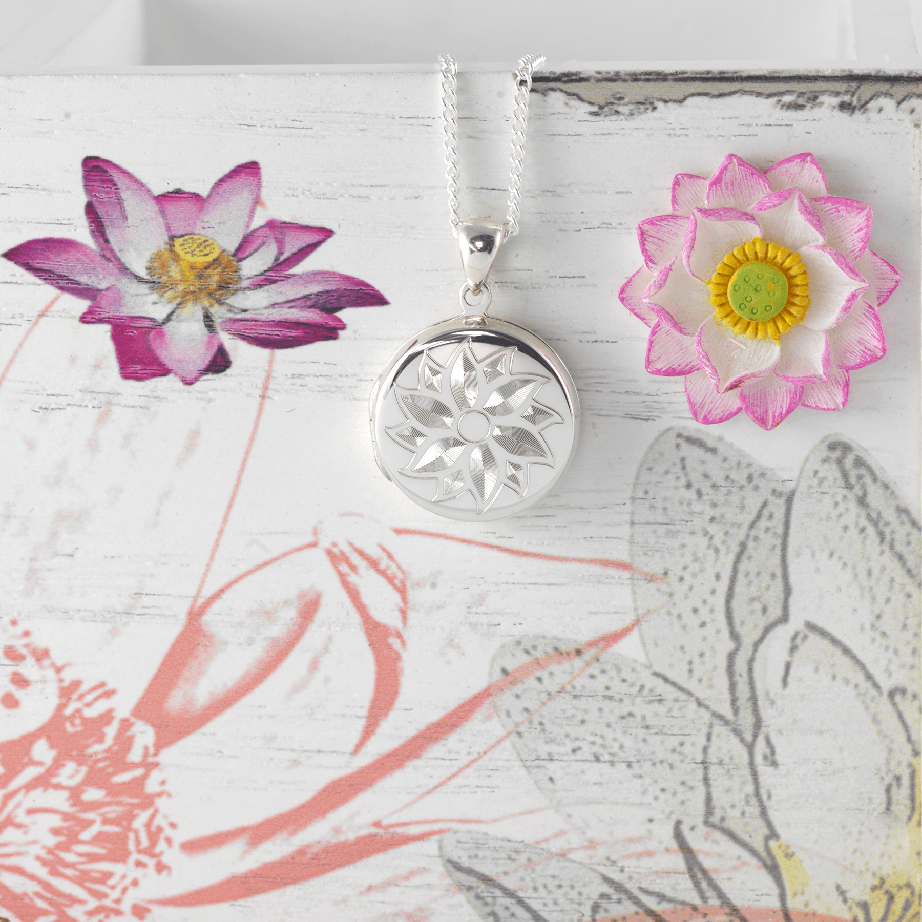 Sterling silver round locket engraved with a flower design on a sterling silver curb chain.