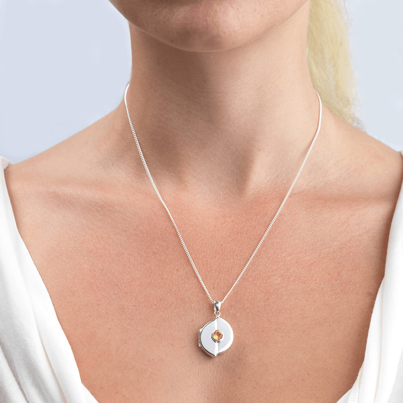 Model wearing a circular 9 ct white gold locket set with a yellow citrine on a 9 ct white gold curb chain