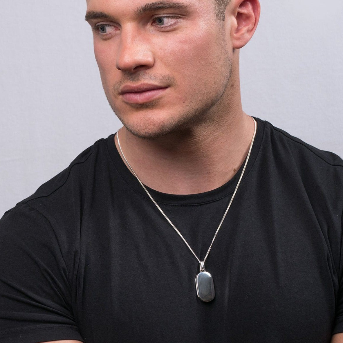 Model wearing a sterling silver dog tag shaped locket on a sterling silver curb chain