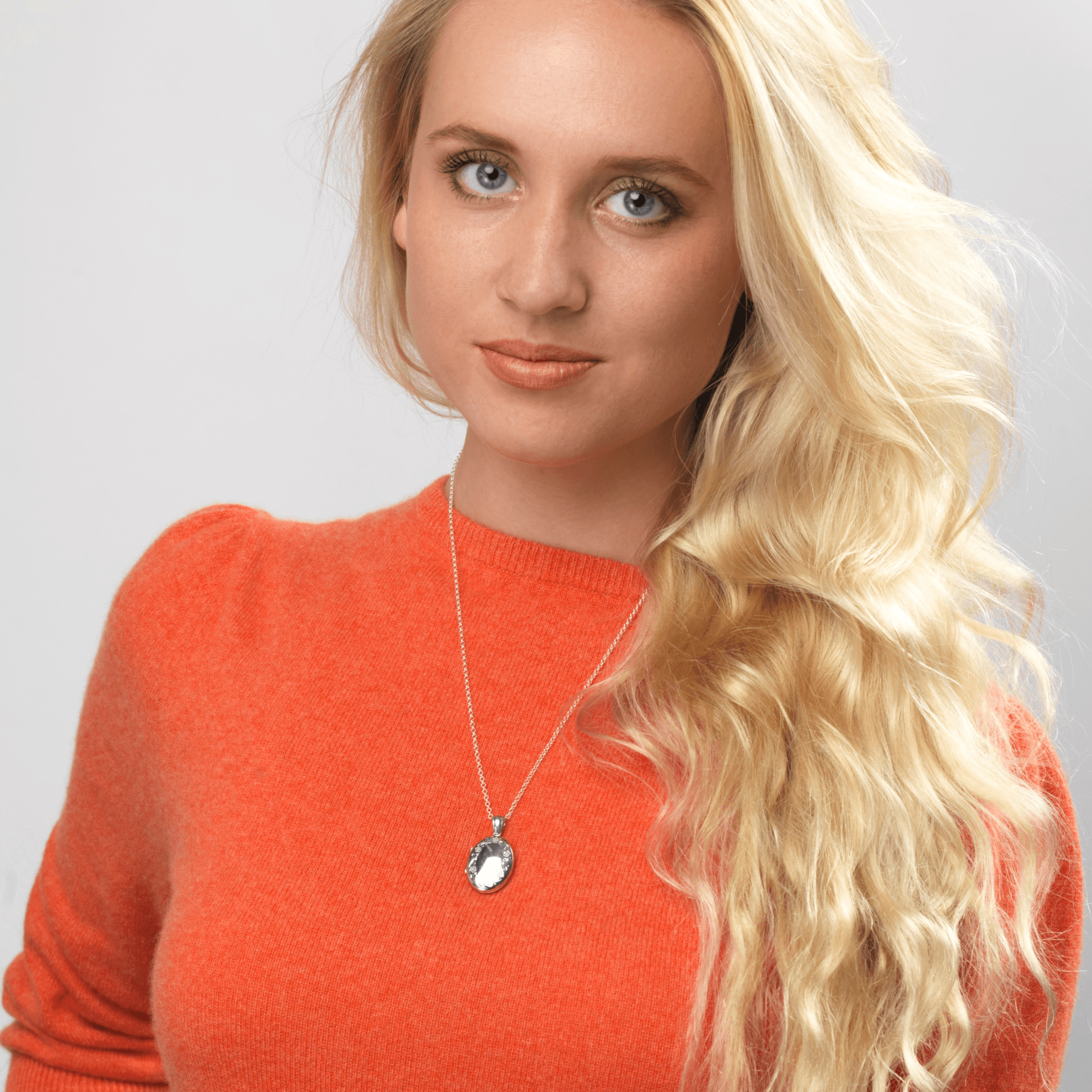 Model wearing a platinum oval locket engraved with a floral border design on a plattinum chain