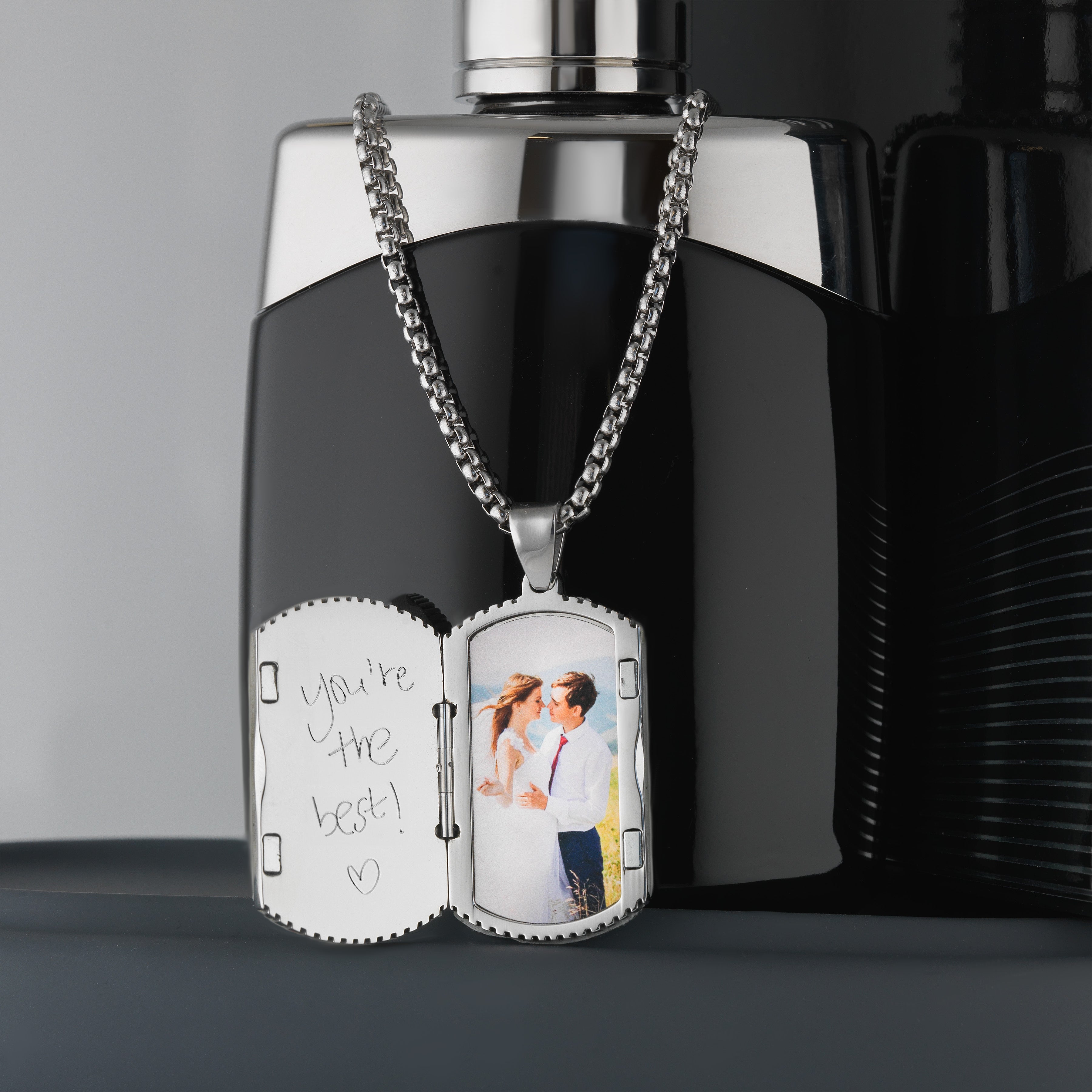 Photo of the inside of a stainless steel and forged carbon fibre men's dog tag locket placed on sterling silver chain.