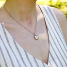 Model wearing a premium petite white gold heart locket with a star set diamond in the middle and placed on a curb chain.