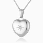 Close up photo of a premium petite white gold heart locket with a star set diamond in the middle and placed on a curb chain.