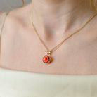 Photo of a model with petite round 9 ct gold locket with a red coral in the middle and matching rubies surrounding it placed on a 9 ct gold base with a 9ct gold chain accompanying it.