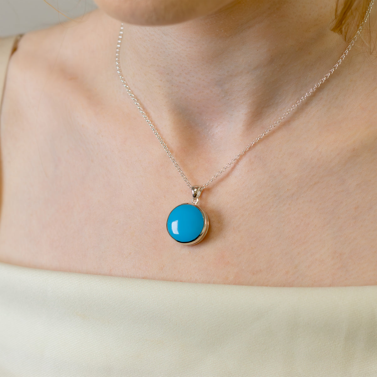 model wearing a sterlig silver round locket set with blue turquoise