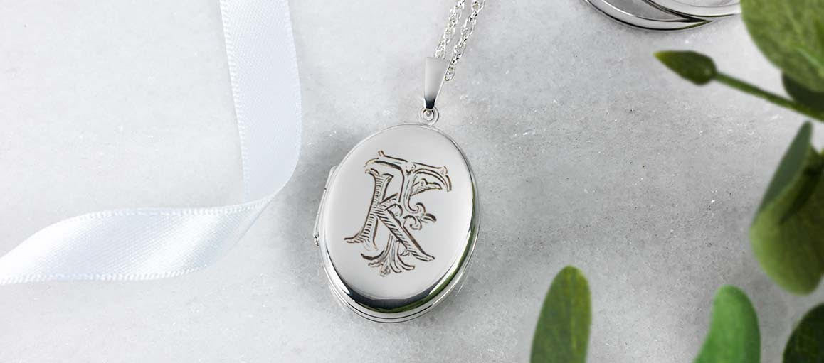 An ornate monogram engraved on a silver oval locket