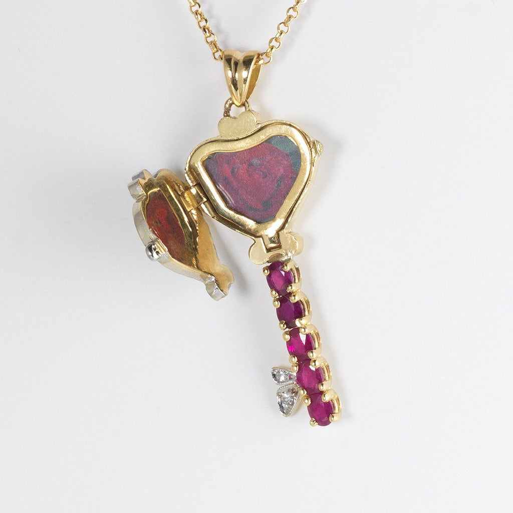 Open view of an 18 ct gold locket in the shape of a key set with diamonds and rubies, on an 18 ct gold trace chain