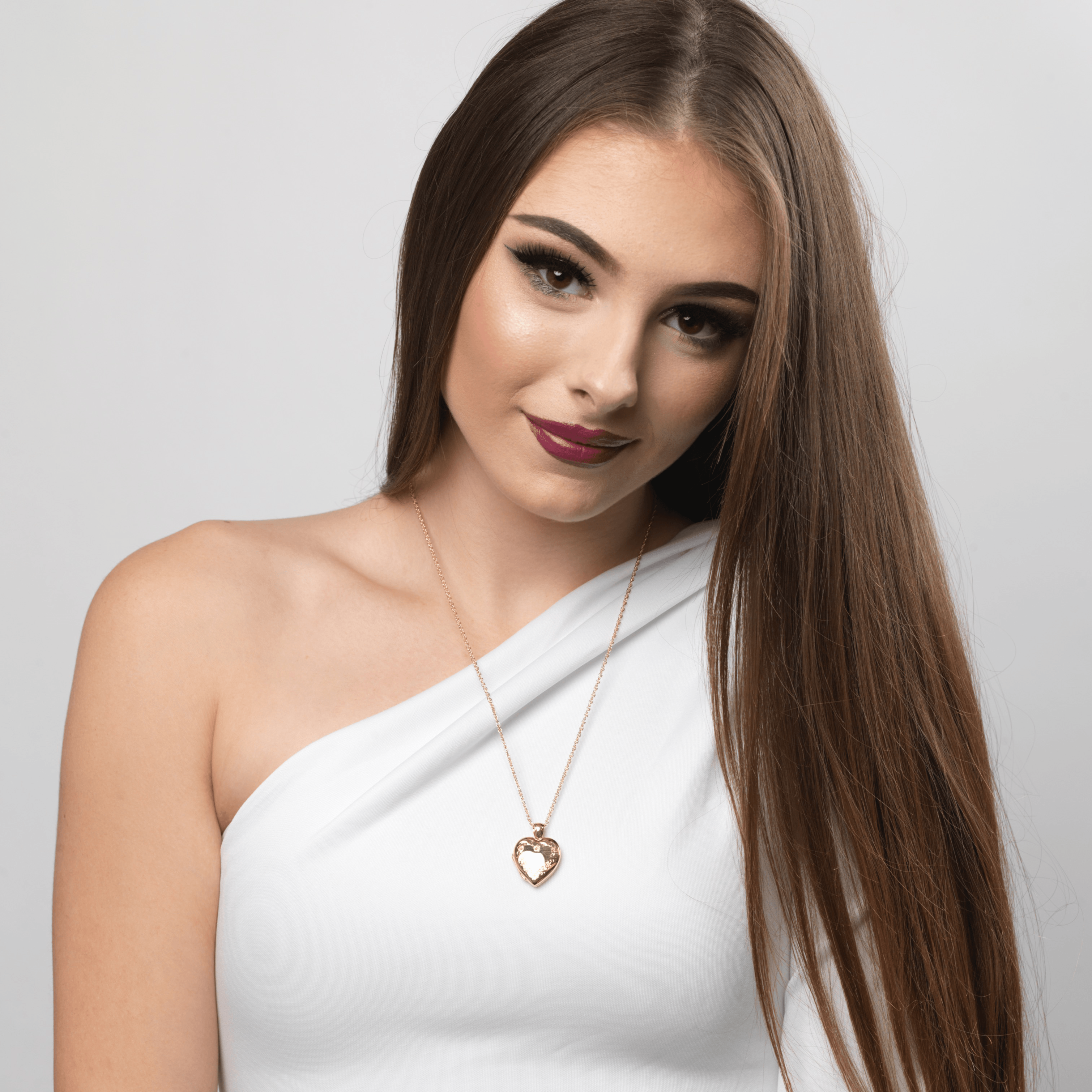Model wearing an 18 ct gold heart locket engraved with a flral border on an 18 ct gold franco chain
