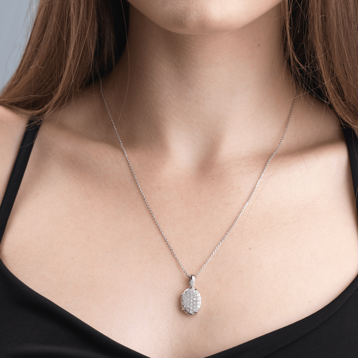 Model wearing a platinum petite oval locket pave set with diamonds on a platinum trace chainet 16 mm, product type: Locket