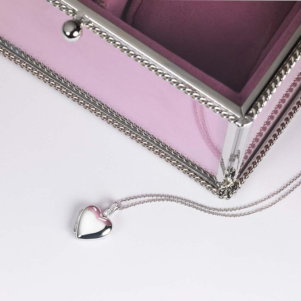 Platinum locket set with diamonds on the bail, alongside an jewellery box, on a white surface.