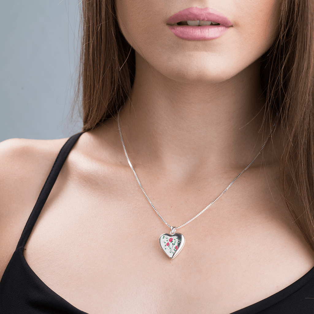 Model wearing a heart-shaped contemporary sterling silver heart locket with a vintage rose and leaves design.