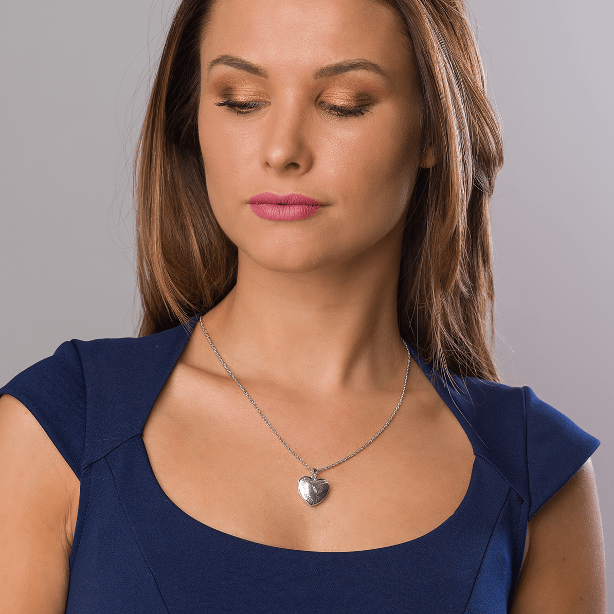 Model wearing a 9 ct white gold heart locket engraved with a bird design on a 9 ct white gold chain