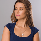 Model wearing a 9 ct gold round locket with an engraved border on a 9 ct gold rope chain
