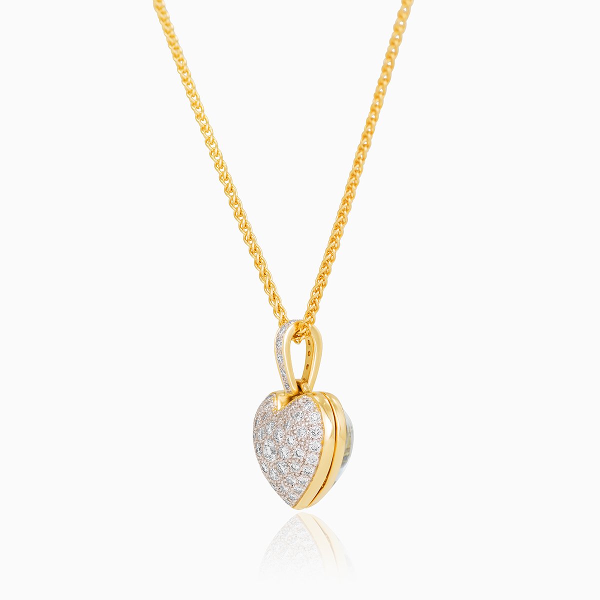 Side view of a petite reversible 18 ct gold heart locket set with aquamarine one one side and diamonds on the other side, on an 18 ct gold chain