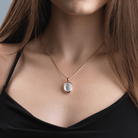 Model wearing an 18 ct gold oval locket set with mother of pearl and a central diamiond, on an 18 ct gold franco chain