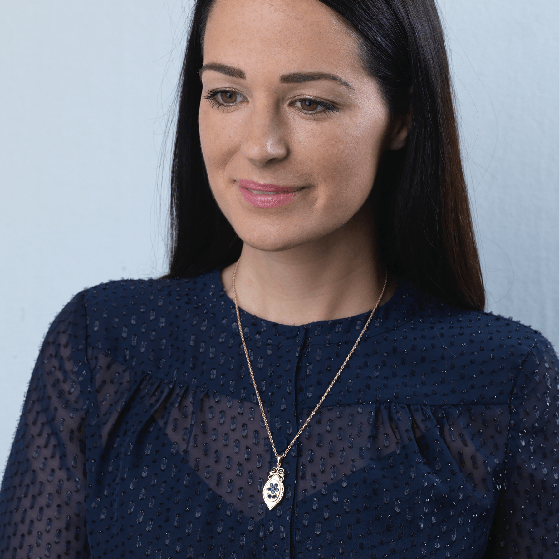 Model wearing an elongated 9 ct gold locket set with sapphires on a 9 ct gold rope chain