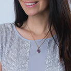 Model wearing a 9 ct gold teardrop shaped locket set all over with purple amethyst stones, on a 9 ct gold rope chain