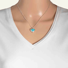 Model wearing a petite heart-shaped sterling silver locket set with reconstituted turquoise.