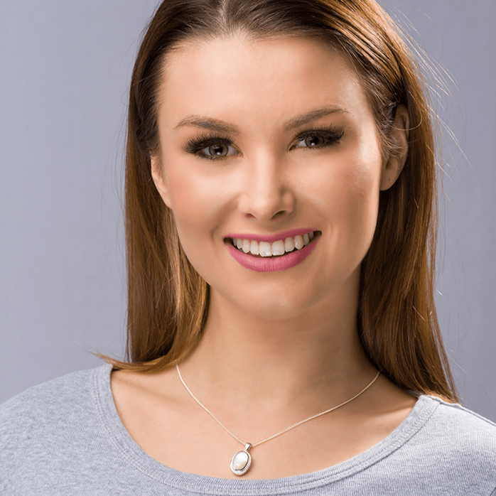 Model wearing a sterling silver oval lockert set with pink mother of pearl and a rope twist border on a sterling silver rope chain.