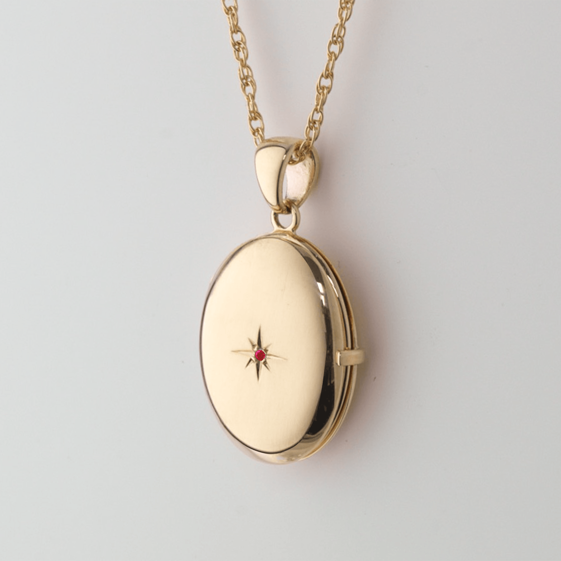 9 ct gold oval 4-photo locket set with a ruby on a 9 ct gold rope chain