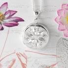 Sterling silver round locket engraved with a flower design on a sterling silver curb chain.