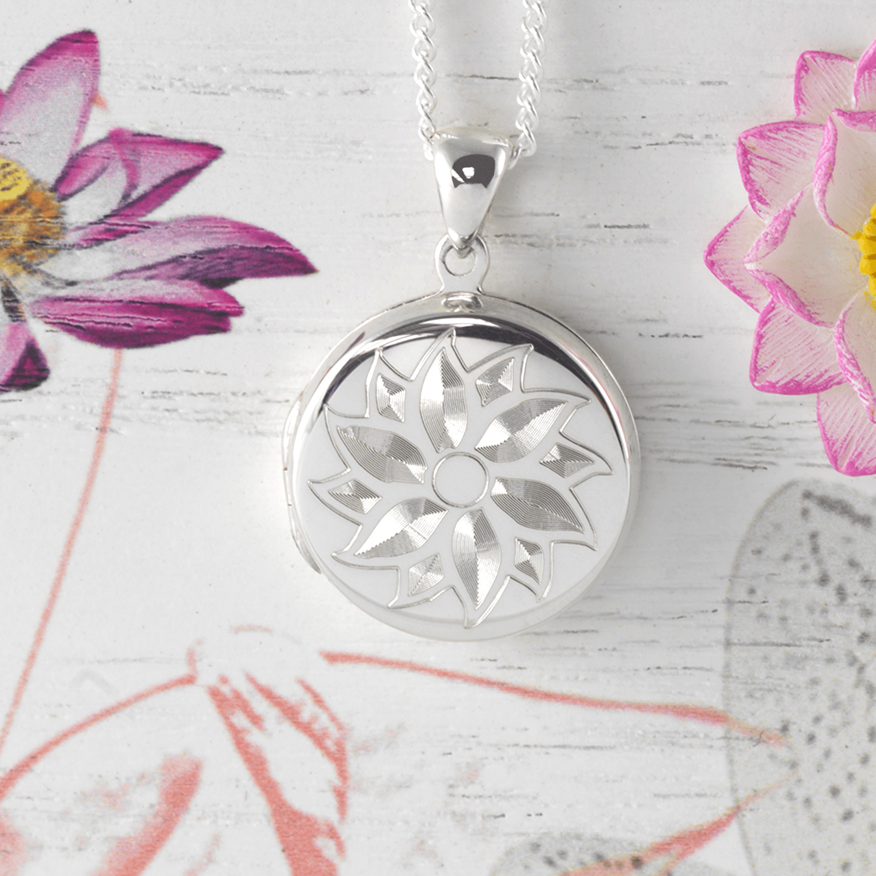 Sterling silver round locket engraved with a flower design on a sterling silver curb chain.