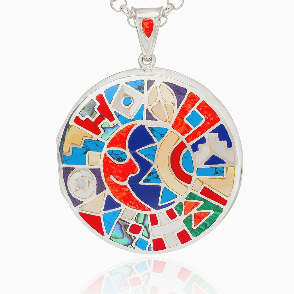 extra large locket in sterling silver, inlaid with a mosaic of gemstones: mother-of-pearl, agate, lapis lazuli, malachite, turquoise and coral. A sun and moon motif can be discerned within the vibrant display of colour.