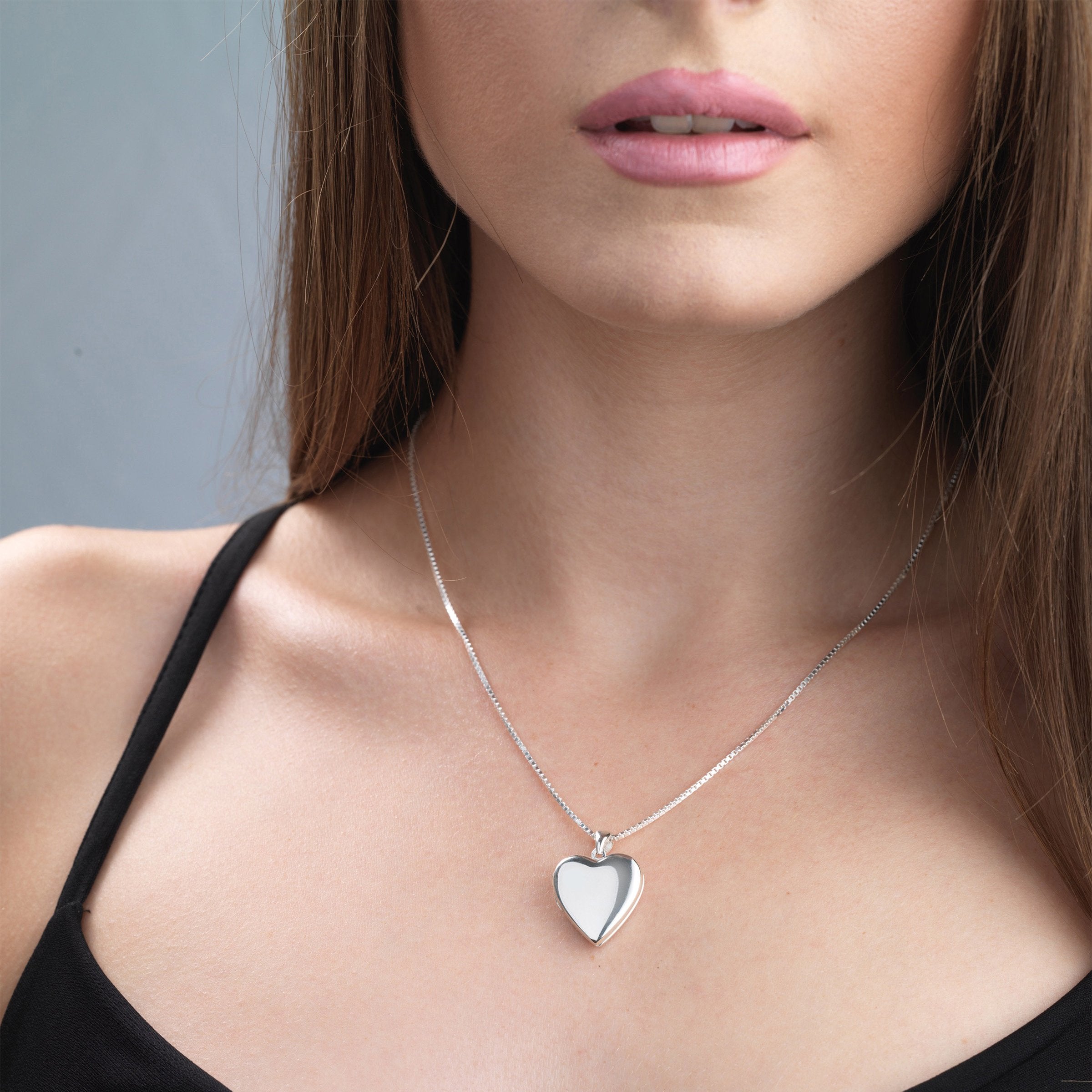 Model wearing a heart-shaped contemporary sterling silver heart locket. 